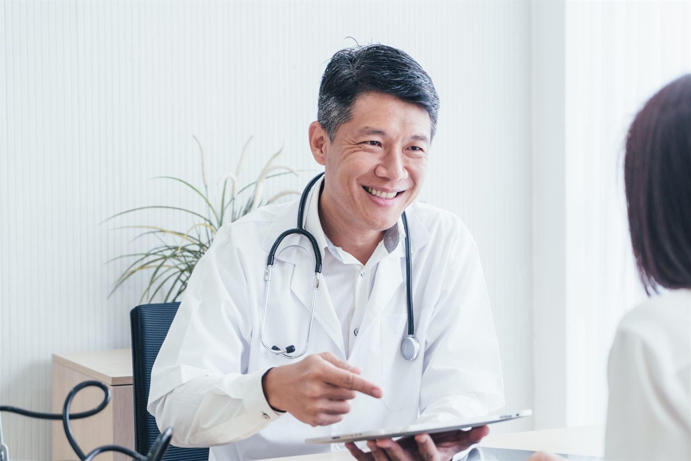 A doctor reviewing notes on a tablet with a patient during a consultation