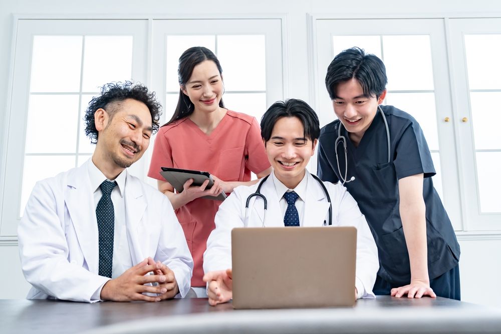 A team of healthcare professionals collaborating around a laptop