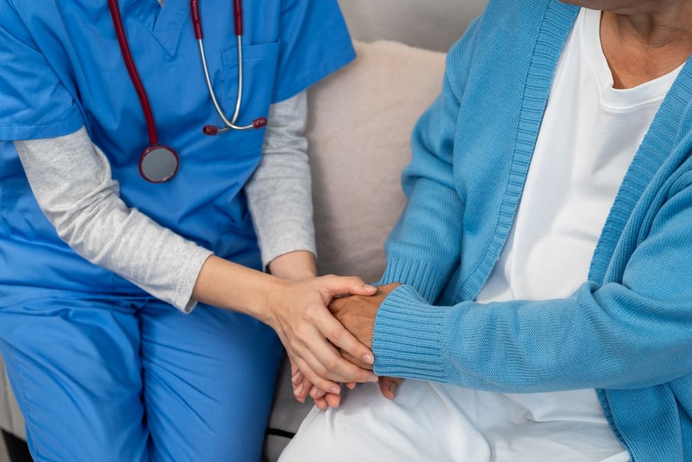 A care worker gently holding a patient's hand